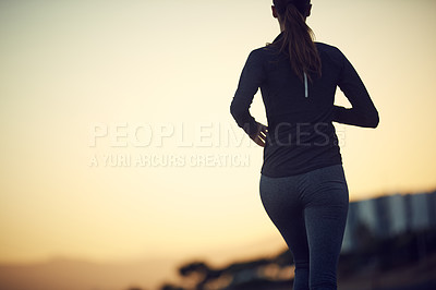 Buy stock photo Rearview shot of a sporty young woman exercising outdoors