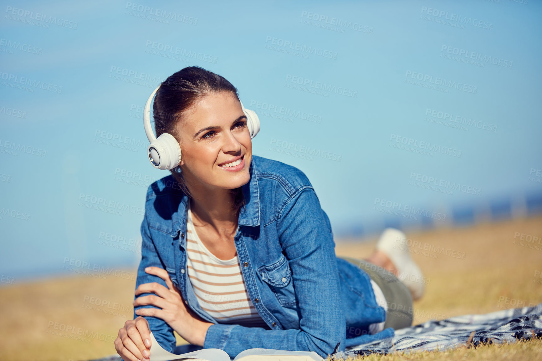 Buy stock photo Shot of an attractive young woman using headphones while relaxing in the park