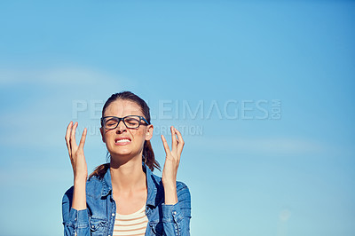 Buy stock photo Shot of a young woman looking frustrated outdoors