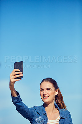 Buy stock photo Shot of an attractive young woman taking a selfie outdoors