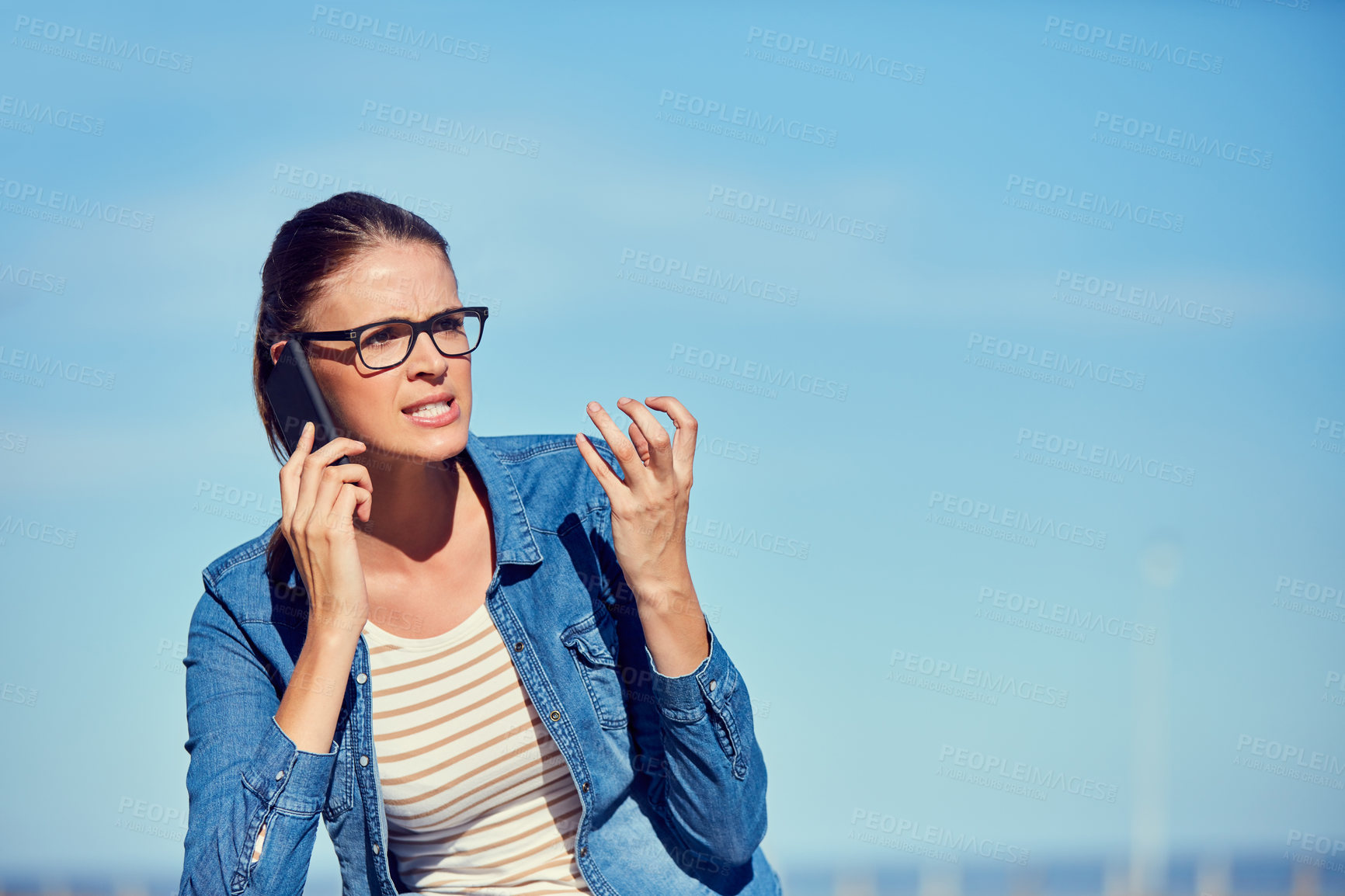 Buy stock photo Shot of an attractive young woman using a mobile phone outdoors and looking angry