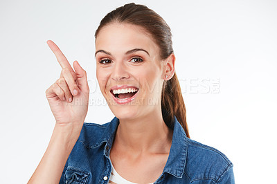 Buy stock photo Studio portrait of a young woman pointing against a grey background