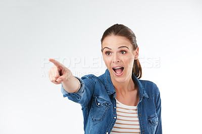 Buy stock photo Studio shot of a young woman pointing against a grey background
