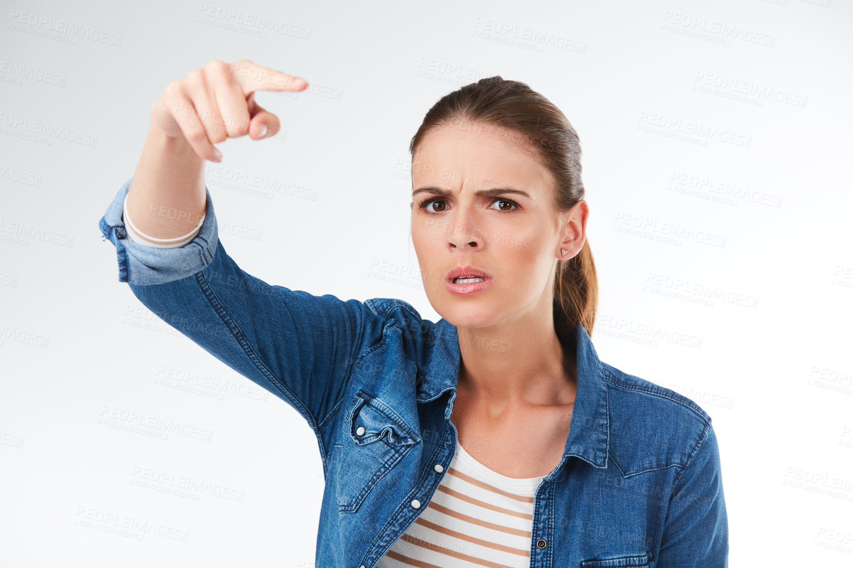 Buy stock photo Studio portrait of a young woman pointing a finger in anger against a grey background