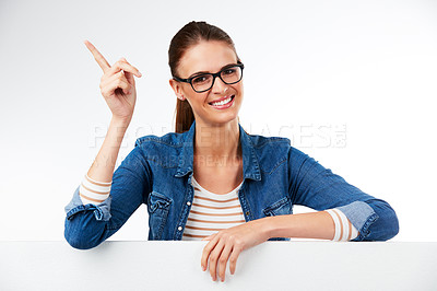Buy stock photo Studio portrait of a young woman posing with a blank placard and pointing against a grey background