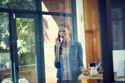 Buy stock photo Shot of a young businesswoman using a mobile phone and looking angry in a modern office