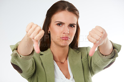 Buy stock photo Studio portrait of a young woman showing a thumbs down gesture against a grey background