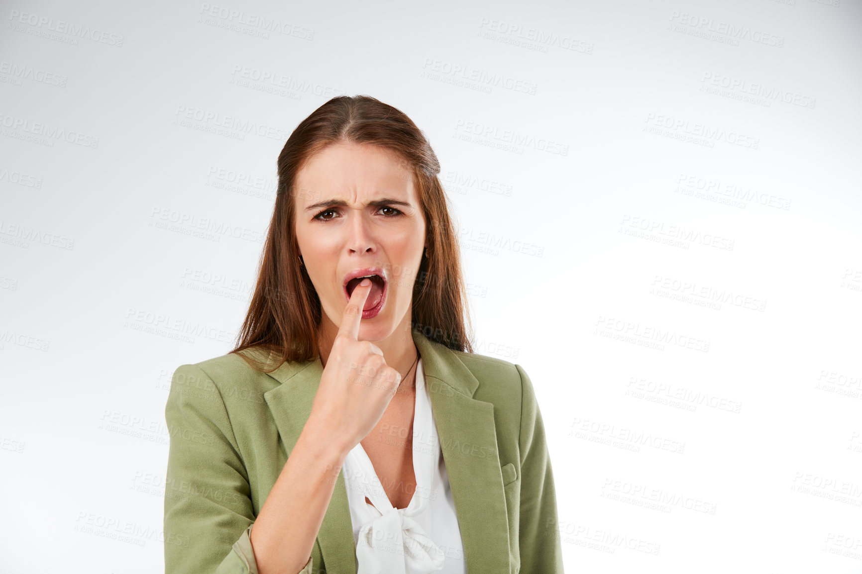 Buy stock photo Studio portrait of a young woman putting her finger in her mouth in disgust against a grey background