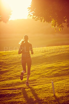 Buy stock photo Rearview shot of a sporty young woman exercising outdoors