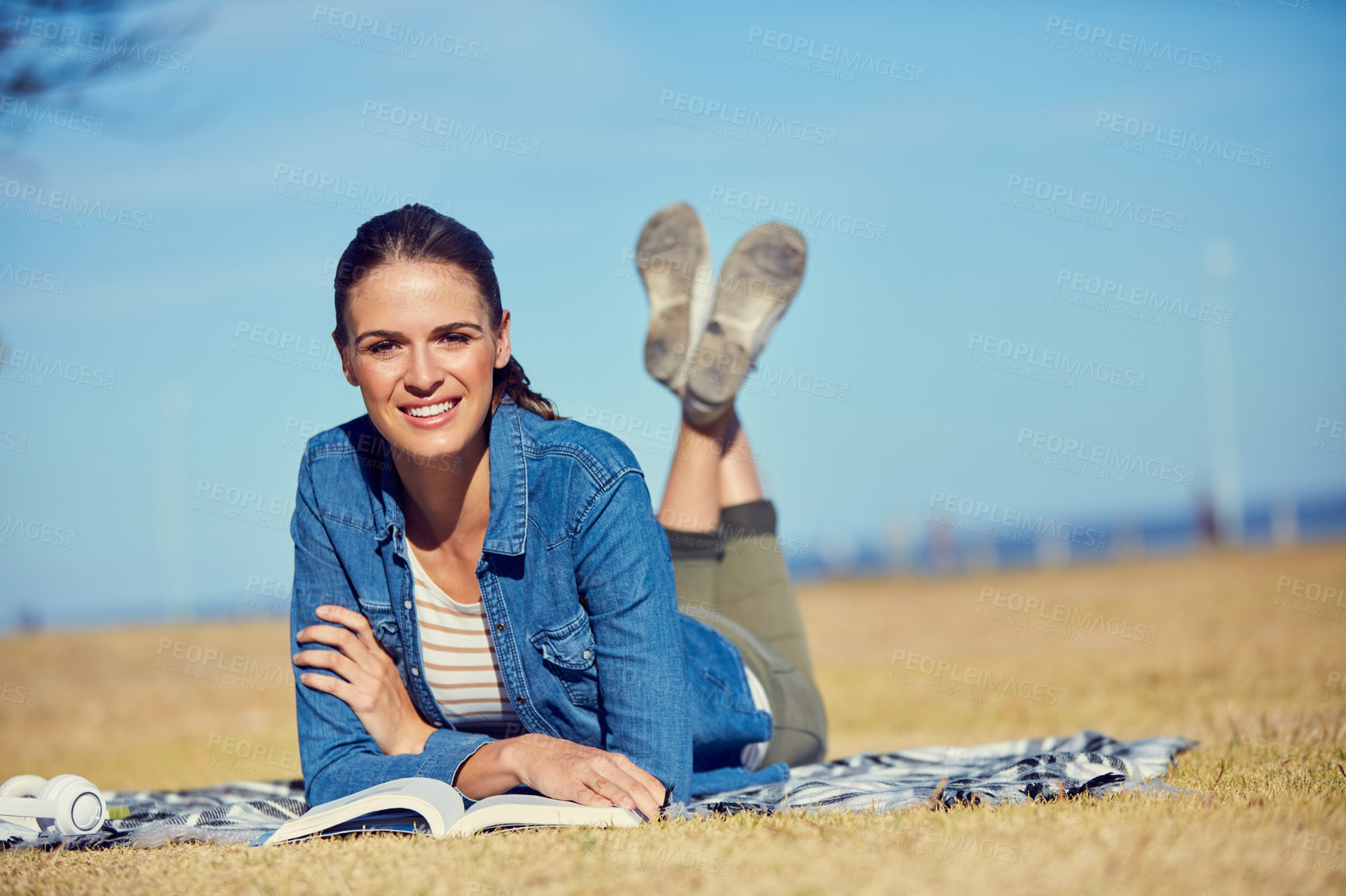 Buy stock photo Portrait of an attractive young woman reading a book while relaxing in the park