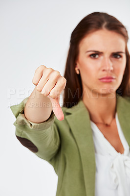 Buy stock photo Studio portrait of a young woman showing a thumbs down gesture against a grey background