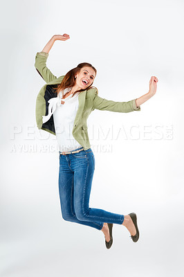 Buy stock photo Studio portrait of a happy young woman jumping for joy against a grey background