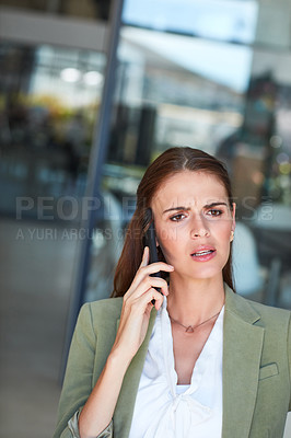 Buy stock photo Shot of a young businesswoman using a mobile phone and looking annoyed in a modern office