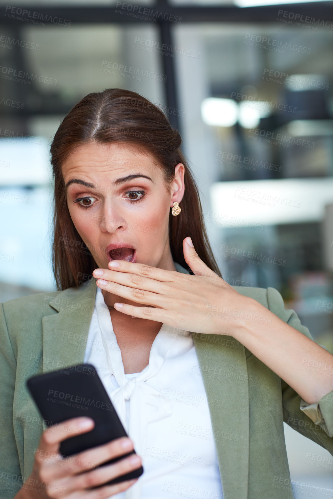 Buy stock photo Shot of a young businesswoman using a mobile phone and looking shocked in a modern office