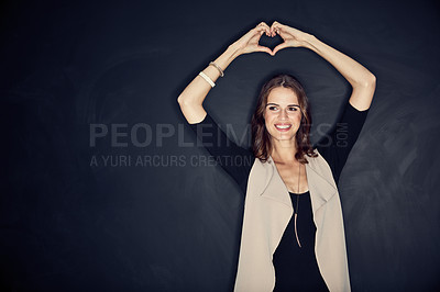 Buy stock photo Studio shot of an attractive young woman forming a heart shape with her hands