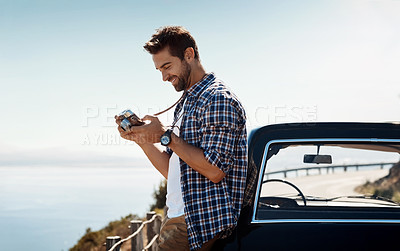 Buy stock photo Shot of a man looking at his camera while out on a road trip