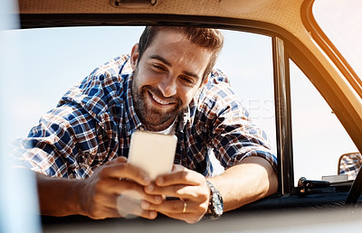 Buy stock photo Cropped shot of a handsome man sending a text while enjoying a road trip