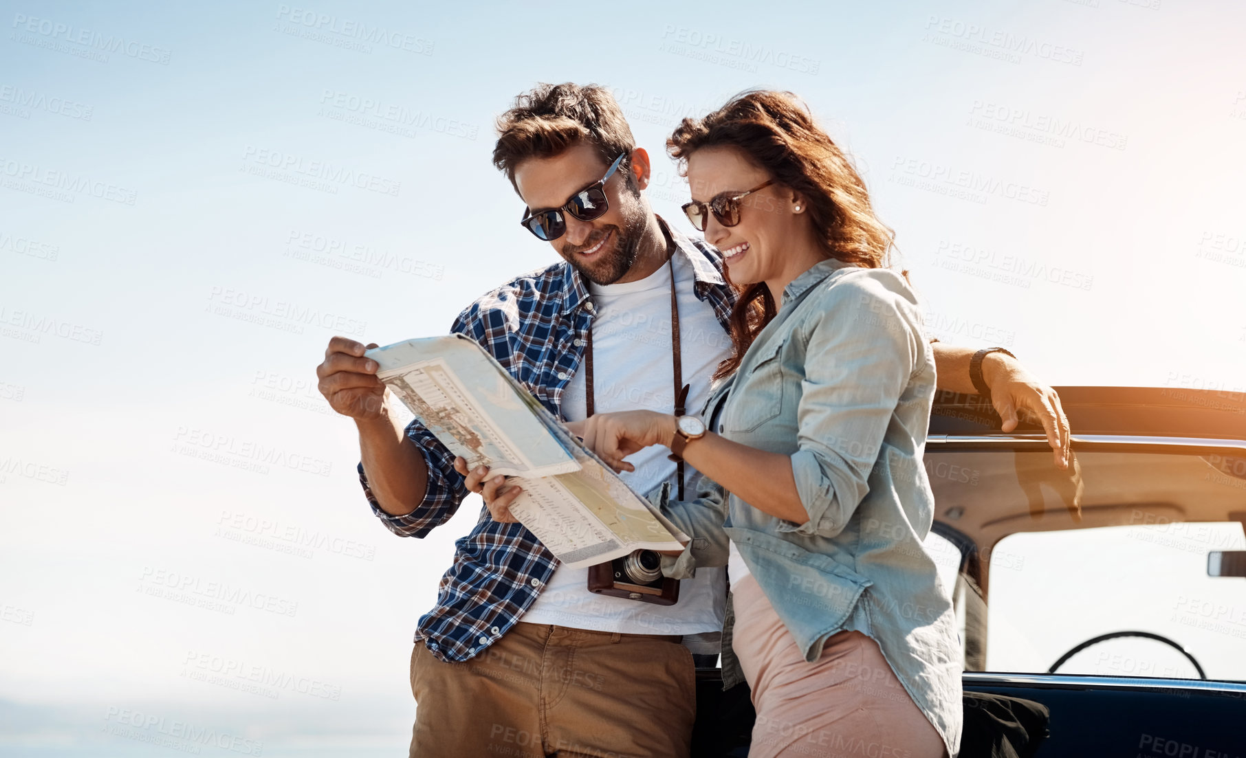 Buy stock photo Cropped shot of an affectionate couple looking at a map while enjoying a road trip