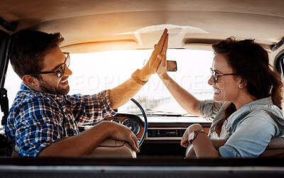 Buy stock photo Rearview portrait of an affectionate couple giving each other a high five while enjoying a road trip