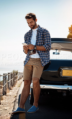 Buy stock photo Shot of a handsome man sending a text while enjoying a road trip
