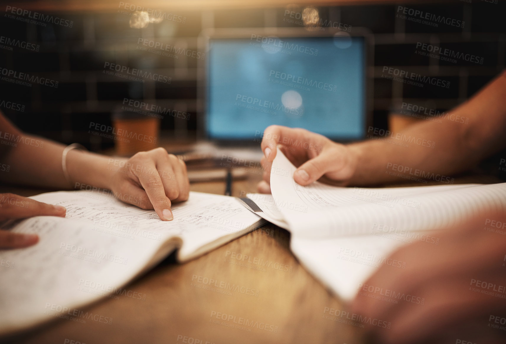 Buy stock photo Cropped shot of two unrecognizable students having a study session at a table in a cafe