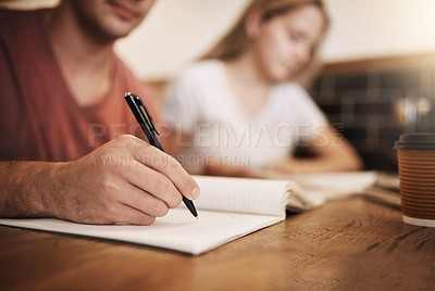 Buy stock photo Cropped shot of two unrecognizable students having a study session at a table in a cafe