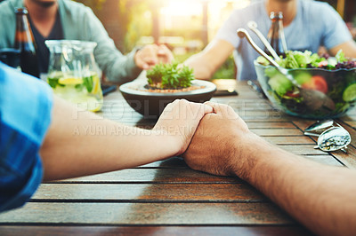 Buy stock photo Closeup shot of an unrecognizable group of young friends holding hands together around a table outside in a garden