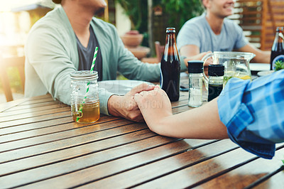 Buy stock photo Closeup shot of an unrecognizable group of young friends holding hands together around a table outside in a garden
