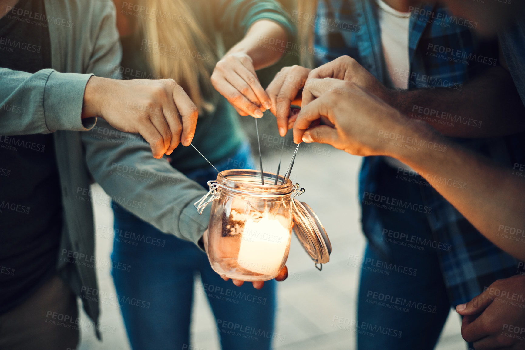 Buy stock photo Shot of a group unrecognizable people's hands lighting up sparklers together outside