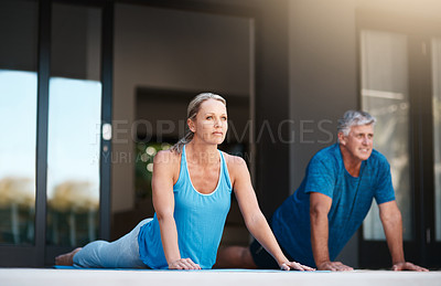 Buy stock photo Full length shot of a mature and happy couple doing yoga exercises outside of their home