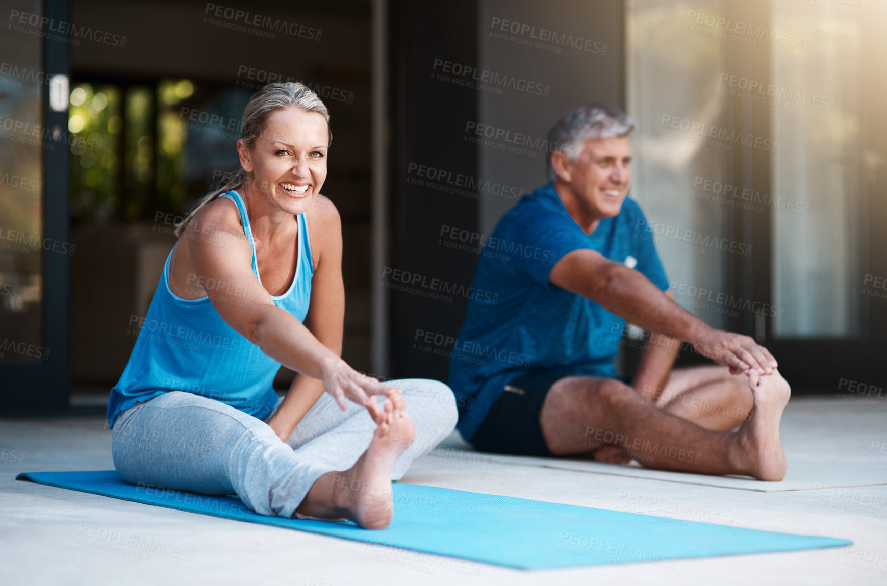 Buy stock photo Shot of a mature and happy couple stretching before they begin their yoga session outside of their home
