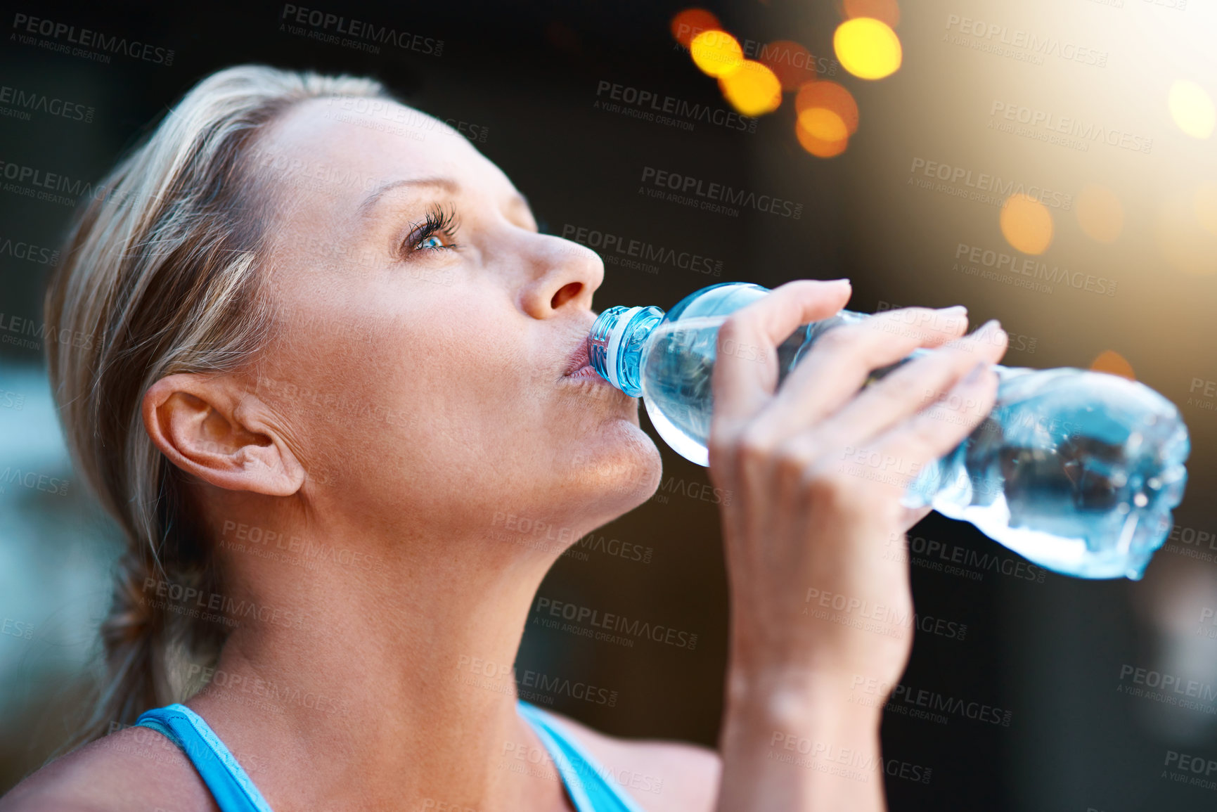 Buy stock photo Shot of a mature woman drinking water out of a bottle outdoors