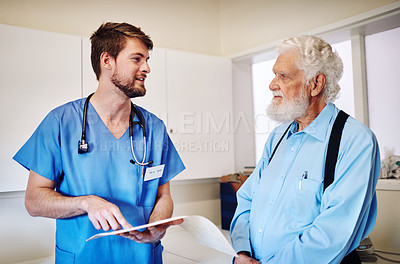Buy stock photo Shot of a young doctor going through medical records with a senior patient at a hospital
