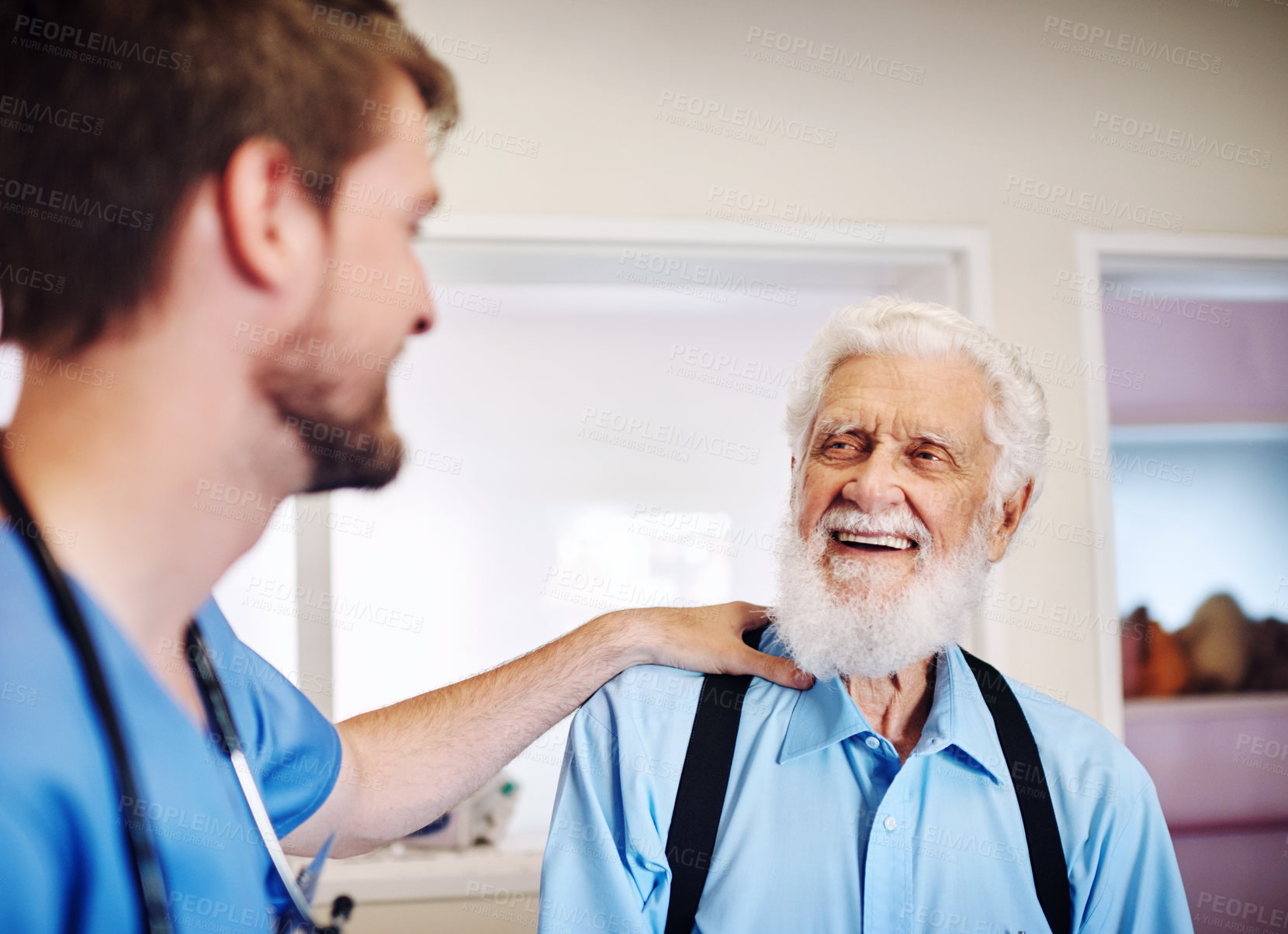 Buy stock photo Shot of a young doctor putting his hand on a senior man's shoulder in comfort at a clinic