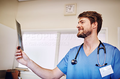 Buy stock photo Shot of a young doctor analyzing an x-ray alone in his office