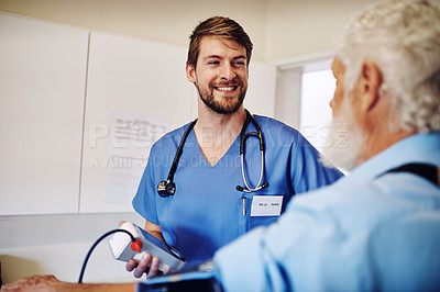 Buy stock photo Shot of a young doctor monitoring his senior patient's blood pressure in the hospital