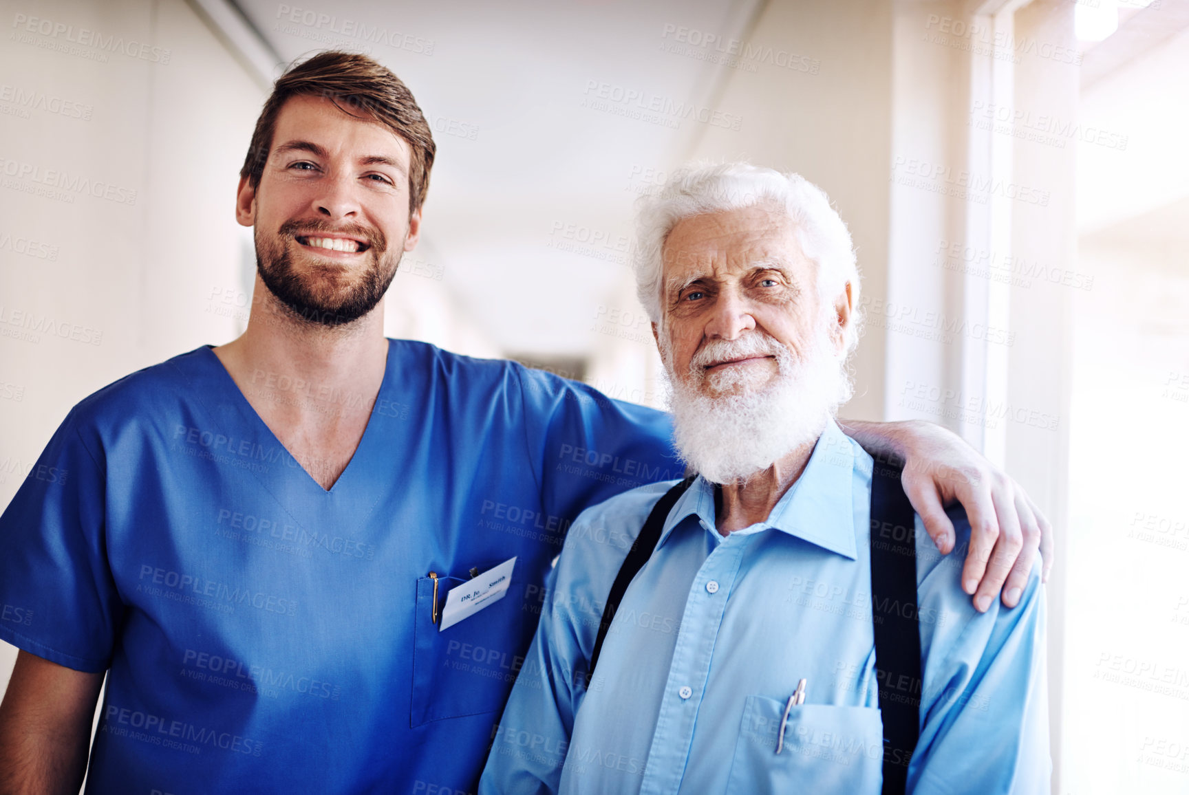 Buy stock photo Portrait of a young doctor and his senior patient posing together in the hospital