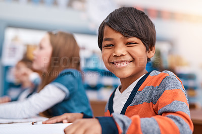 Buy stock photo Portrait of a cheerful young elementary school kid sitting in class during the day