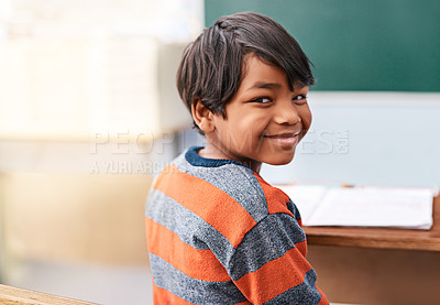 Buy stock photo Portrait of a cheerful young elementary school kid sitting in class during the day