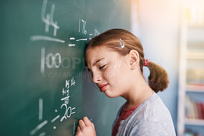 Buy stock photo Cropped shot of a stressed young elementary school kid writing answers to math questions on a green chalkboard in the classroom
