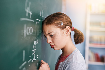 Buy stock photo Cropped shot of a stressed young elementary school kid writing answers to math questions on a green chalkboard in the classroom