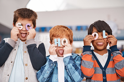 Buy stock photo Cropped shot of a group of cheerful elementary school children holding letters over their faces spelling the word school inside of the classroom