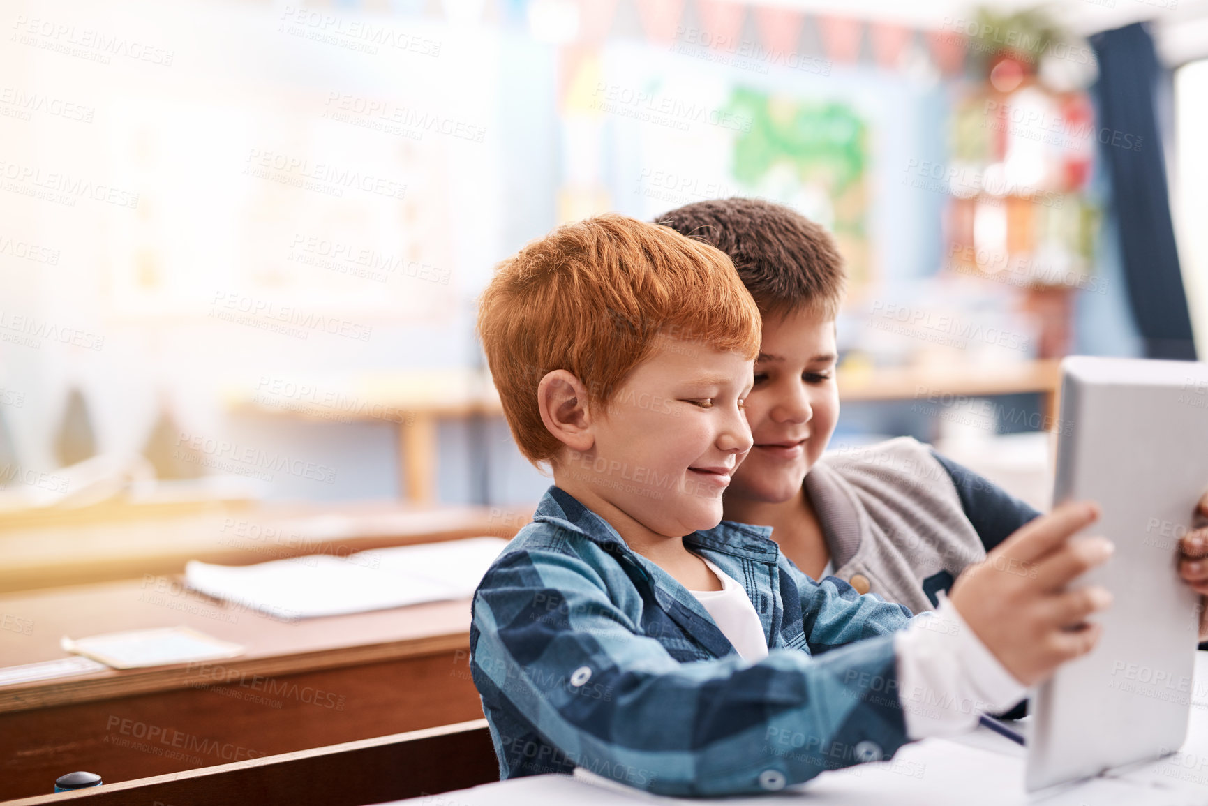 Buy stock photo Cropped shot of two elementary school children browsing on a digital tablet inside of the class during the day