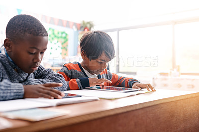 Buy stock photo Cropped shot of two elementary school children browsing on a digital tablet inside of the class during the day