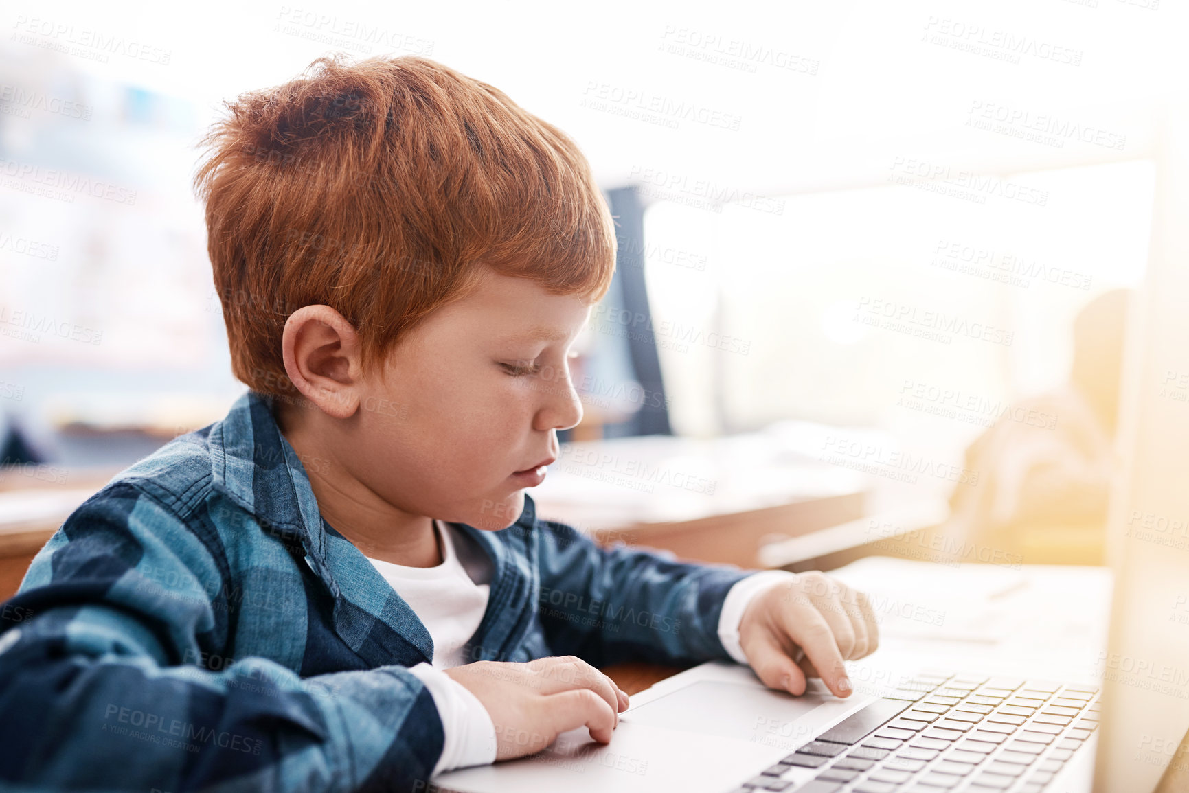Buy stock photo Cropped shot of a focussed young elementary school kid browsing on a laptop inside of the class during the day