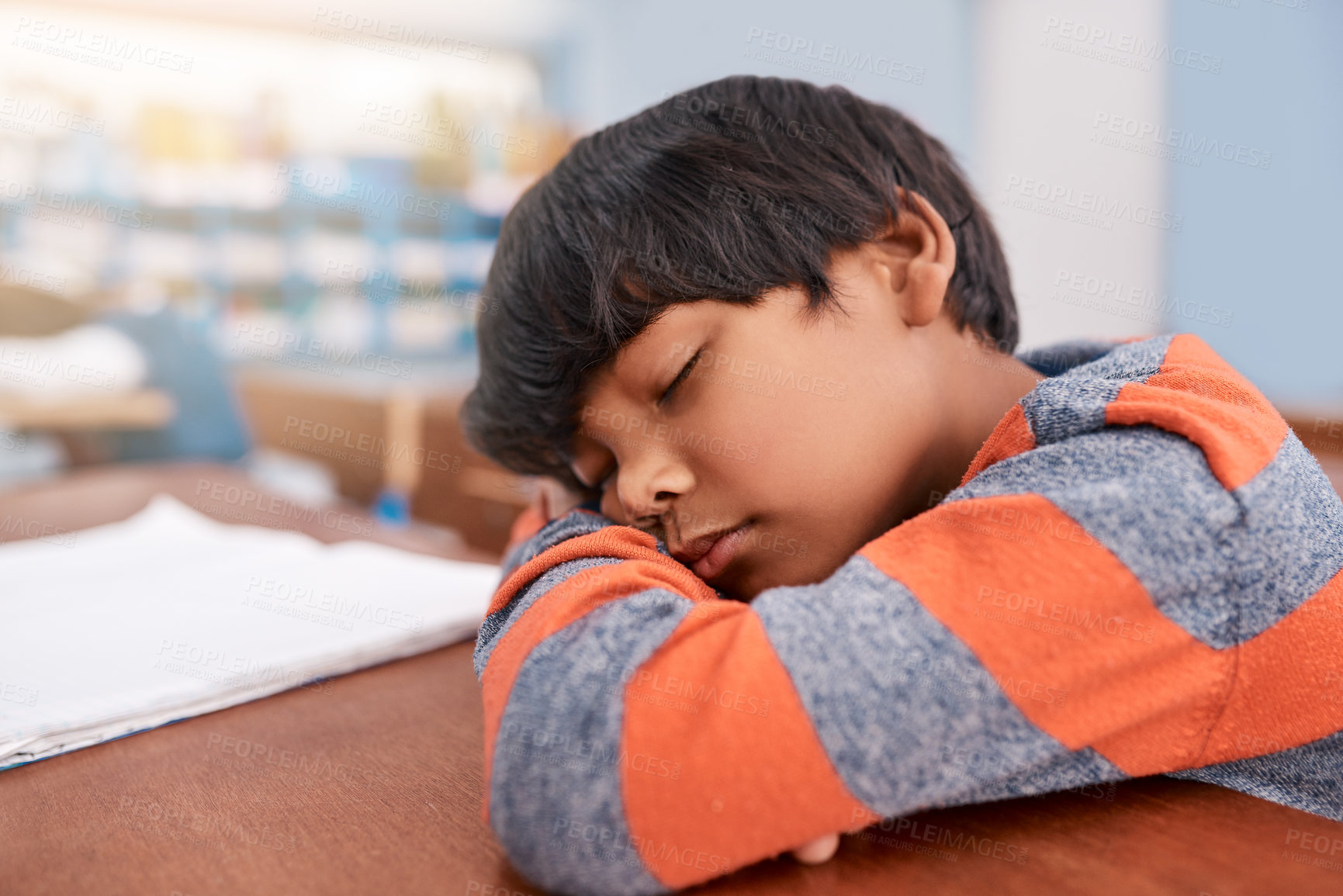 Buy stock photo Cropped shot of a tired elementary school child sleeping on his desk in the classroom