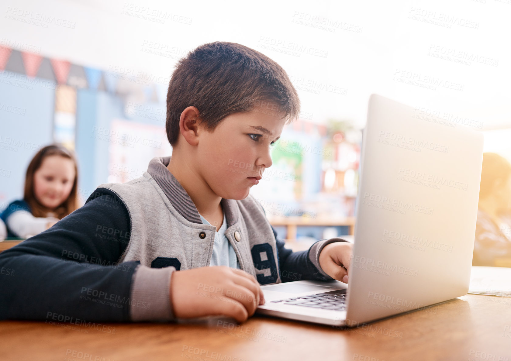 Buy stock photo Cropped shot of a focussed young elementary school kid browsing on a laptop inside of the class during the day