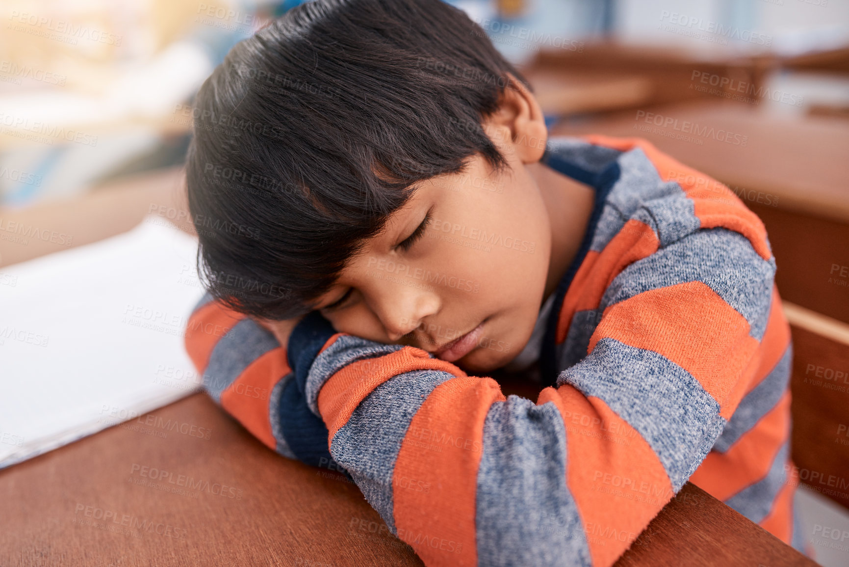 Buy stock photo Cropped shot of a tired elementary school child sleeping on his desk in the classroom