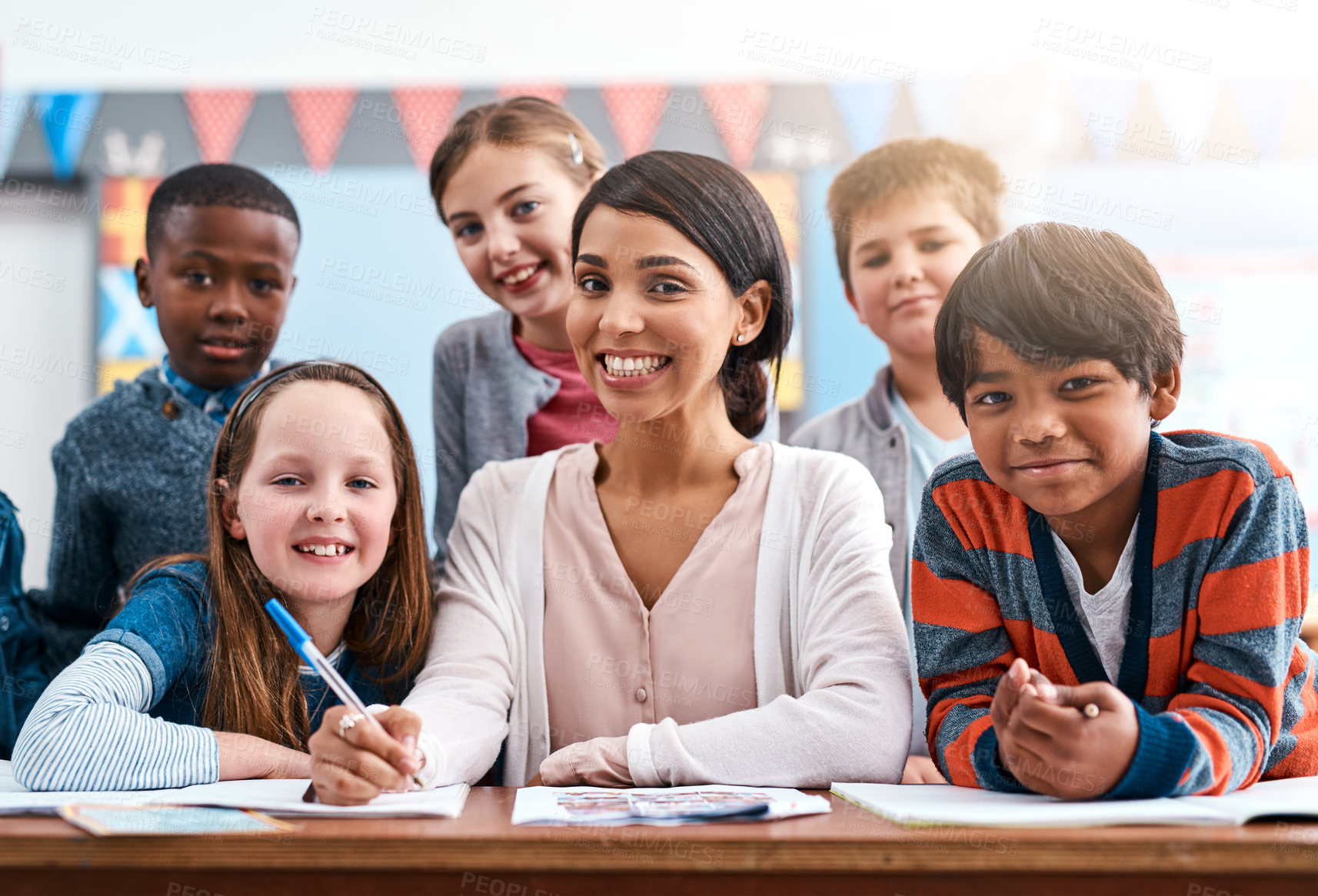 Buy stock photo Portrait of a cheerful young female teacher helping her students inside of the class at school