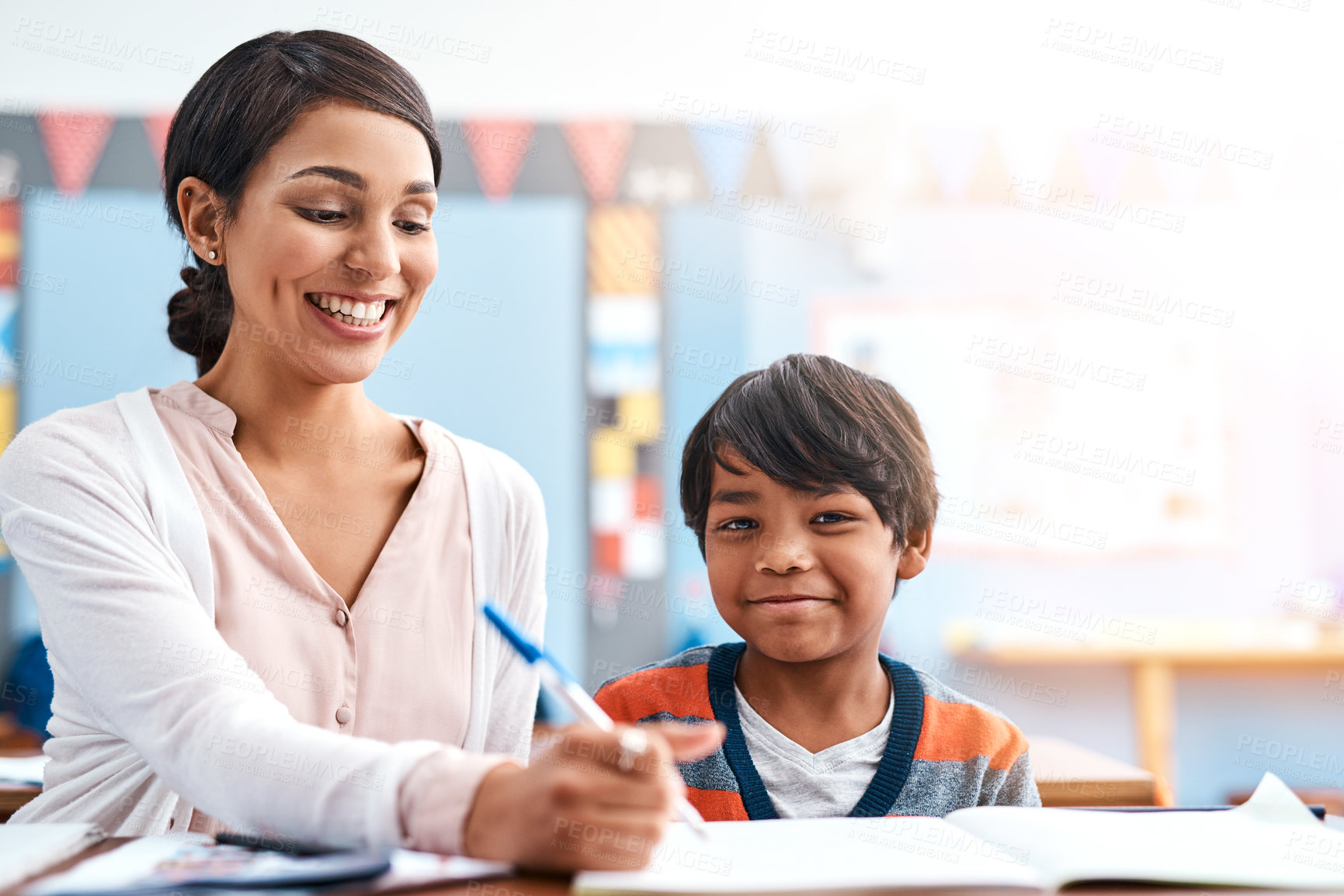 Buy stock photo Shot of a cheerful young female teacher helping a student inside of the class at school